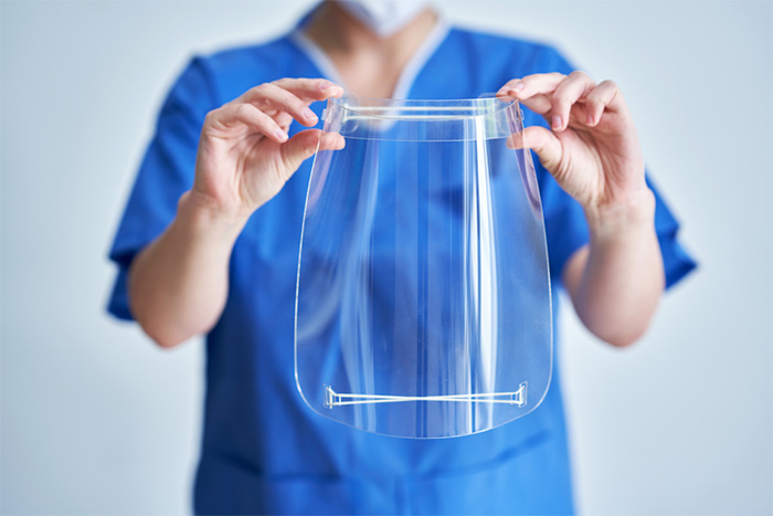 female medical professional wearing scrubs holding protective gear