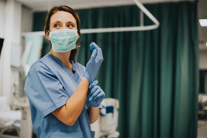 female nurse in mask putting on gloves