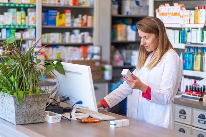 female pharmacist holding medication at pharmacy counter