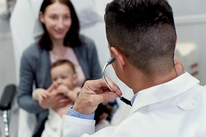 doctor using stethoscope with mother and baby