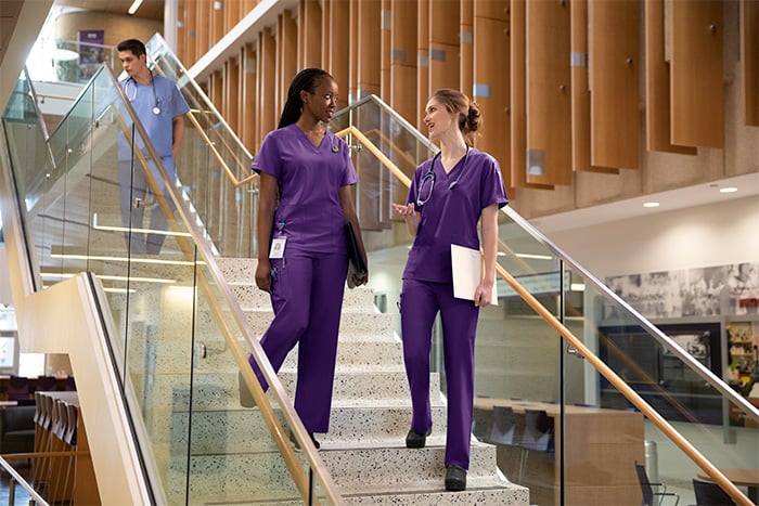 women walking on stairs in purple scrubs