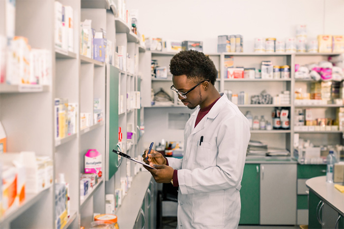 male pharmacist with clipboard checking shelves