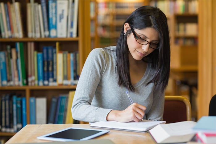 woman with textbooks studying at the library