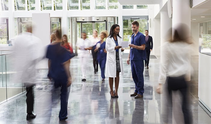 doctor and nurse talking in crowded lobby