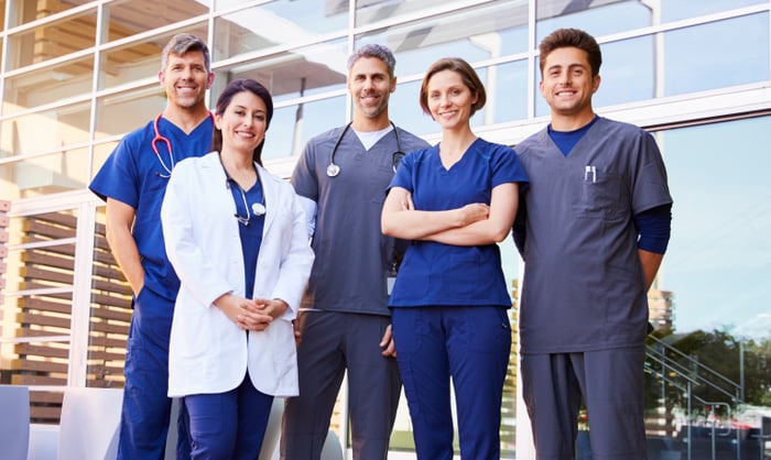 a group of smiling healthcare workers outside hospital