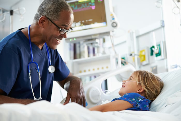 young girl smiling with male pediatric nurse