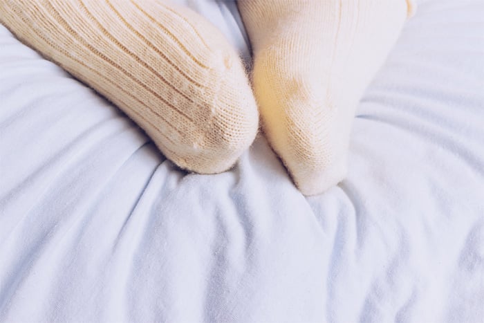 person wearing light socks in bed