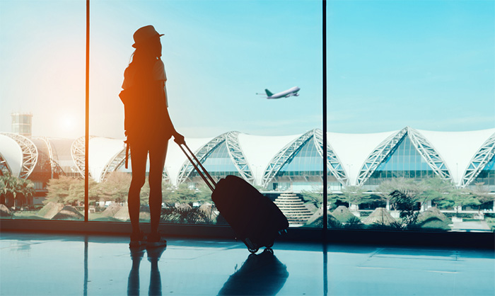 woman with luggage waiting for flight at airport