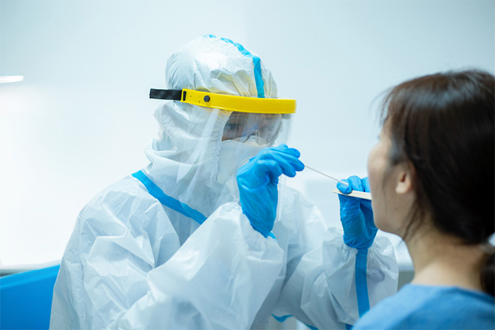 healthcare worker in protective gear testing patient for coronavirus