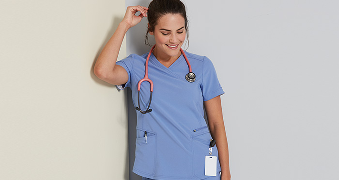 smiling woman wearing blue scrubs and stethoscope